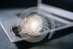 New idea illuminated light bulb on laptop concept for innovation and creativity