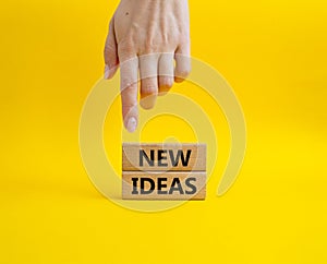 New ideas symbol. Concept word New ideas on wooden blocks. Beautiful yellow background. Businessman hand. Business and New ideas