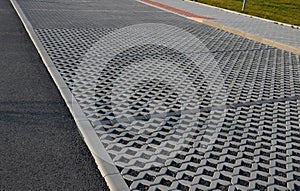 New infiltration parking lot made of porous concrete tiles in a regular square grid with holes filled with gravel. in connection w