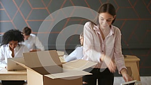 New job concept, young woman unpacking box on office desk