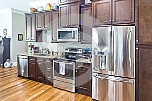 A new kitchen with dark wood cabinets, hardwood floors and stainless steel appliances
