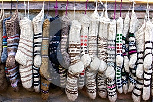 New knitted wool socks of different colors and ornaments hanging in a row photo