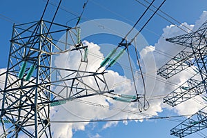 New large mast of an air power line close up, high voltage electricity pylon with thick wires and insulators, blue sky