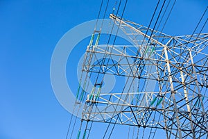 New large mast of an air power line close up, high voltage electricity pylon with thick wires and insulators, blue sky