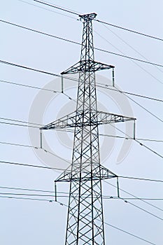 New large mast of an air power line close up, high voltage electricity pylon with thick wires and insulators, blue sky