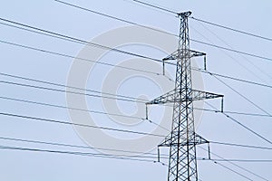 New large mast of an air power line close up, high voltage electricity pylon with thick wires and insulators, blue sky