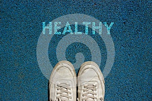 New life concept, Sport shoes and the word HEALTHY ! written on blue Walkway ground, Motivational slogan