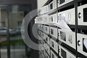 New mailboxes with keyholes, numbers and receipts near entrance in post office, closeup