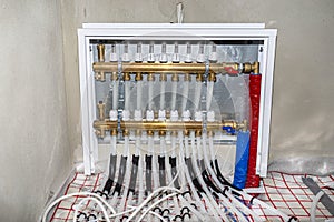 New manifold of underfloor heating system, plastic pipes and valves visible, serving nine circuits.
