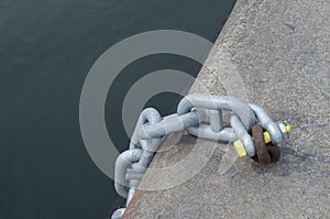 New metal chain attached with a shackle toold rusty ring in the port close