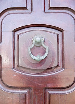 New metal doorknocker on wooden closed brown door