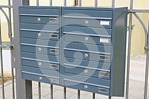 New metallic gray mailboxes hang on an iron grating