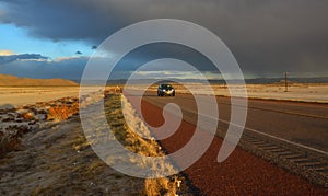 NEW MEXICO, USA - NOVEMBER 22, 2019: car on the road during a red sunset and thunderclouds on the background of the Guadalupe