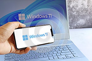 New Microsoft Windows 11 logo on computer screen and Windows 11 logo is seen on mobile phone screen.