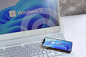 New Microsoft Windows 11 logo on computer screen and Windows 11 logo is seen on mobile phone screen.
