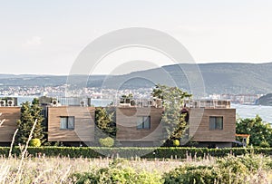 New modern architectural building terraced houses with flat roofs in a row, sea and mountains background