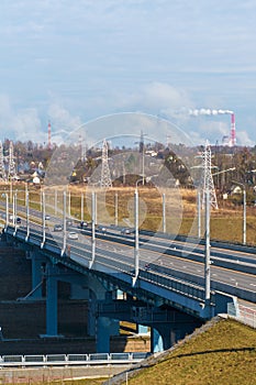 A new modern automobile bridge over the river on the background of the blue sky. A sturdy reinforced concrete bridge, thick