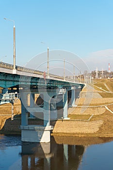 A new modern automobile bridge over the river on the background of the blue sky. A sturdy reinforced concrete bridge, thick