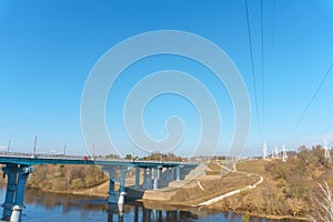 A new modern automobile bridge over the river on the background of the blue sky. A sturdy reinforced concrete bridge, thick