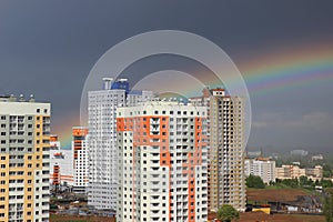 New modern block multistory house on dark sky background in four colors: red, orange, grey and white. Bad weather and rainbow.