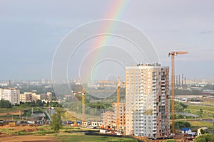 New modern block multistory house on dark sky background in four colors: red, orange, grey and white. Bad weather and rainbow.