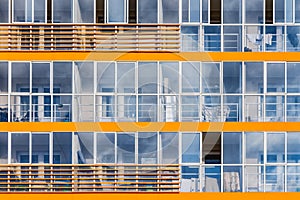 A new modern building of student dormitorie in the campus with many windows with reflections of blue sky with white clouds.