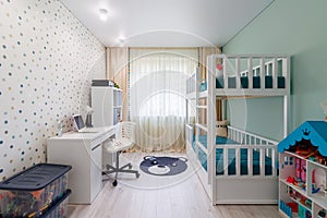 A new modern children`s room with a bunk bed with a workplace and wallpaper in multi -colored peas. New house. Inner photo