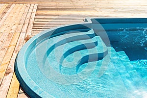 New modern fiberglass plastic swimming pool entrance step with clean fresh refreshing blue water on bright hot summer