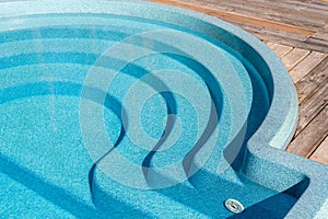 New modern fiberglass plastic swimming pool entrance step with clean fresh refreshing blue water on bright hot summer photo