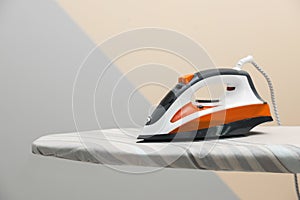 New modern iron on board against color background, space for