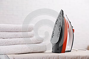 New modern iron and clean towels on board against light background