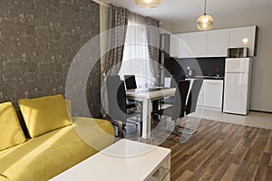 New modern living room. New home. Interior photography. Wooden floor. Dining table with set of chairs, yellow sofa