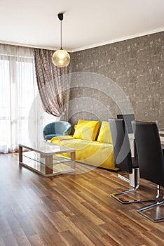 New modern living room. New home. Interior photography. Wooden floor. Dining table with set of chairs, yellow sofa