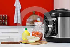 New modern multi cooker and products on table in kitchen