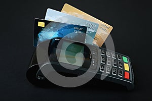 New modern payment terminal with credit cards on black background