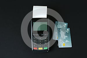 New modern payment terminal and credit cards on black background, flat lay