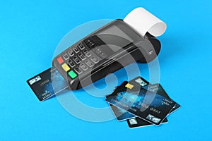 New modern payment terminal and credit cards on light blue background