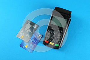 New modern payment terminal and credit cards on light blue background, flat lay