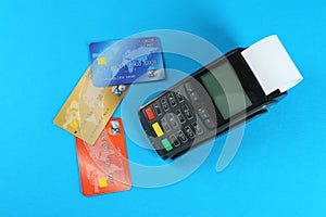 New modern payment terminal and credit cards on light blue background, flat lay