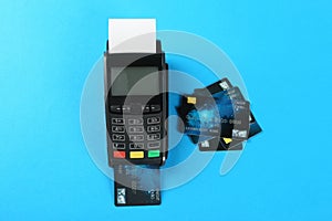 New modern payment terminal and credit cards on light blue background, flat lay