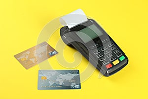 New modern payment terminal and credit cards on yellow background