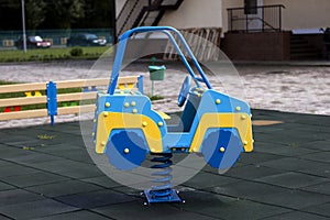 New modern plastic bright colorful blue and yellow big toy car on spring on nursery playground with soft rubber flooring on bright
