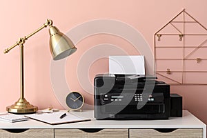 New modern printer with paper on white table at workplace