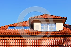 New, modern roof of red ceramic tiles, Dormer window protruding above the roof and three skylights.
