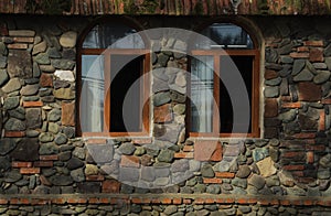 new, modern Wall of building made from cobble stone with 2 two arched windows. exterior background. wooden antique vintage window