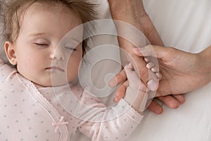 New mom and dad holding hand of beautiful sleepy baby