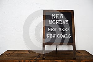 New Monday New Week New Goal text message on easel blackboard standing on wooden shelves