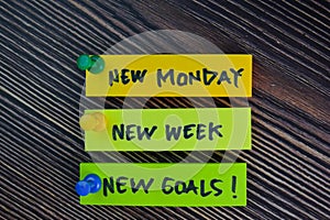 New Monday, New Week, New Goals! write on sticky notes isolated on Wooden Table
