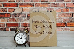 New Monday New Week New Goals text message with alarm clock on wooden background photo