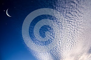 Starry sky with half moon in scenic cloudscape .